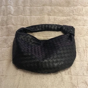 Svart flätad axelväska - Så söt flätad handväska från märket DesignBySi Den är väldigt lik bottega väskan. Köpt för ca 1 år sedan, superbra skick. Den är ii fusk läder, med guld detaljer & har ett mindre innerfack som syns på bilderna. hör bara av dig om du har frågor! <3