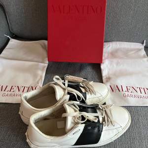 Säljer ett par snygga Valentino Garavani sneakers i vitt med en svart detalj över snörningen. Skorna är i bra skick och kommer med originalförpackning dustbags och nya snören Perfekta för en stilren look! Enda felet är att ett stygn har släppt bild 5