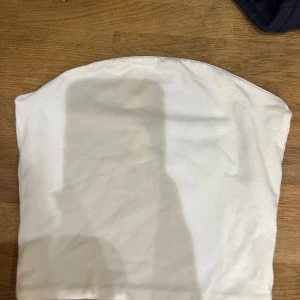 Vit tubtopp från BikBok - Säljer en enkel och stilren vit tubtopp från BikBok i storlek XS. Perfekt för sommardagar eller som basplagg under en kavaj. Toppen är i bra skick och har en mjuk och bekväm passform. Passar till både vardag och fest! Så snygg! Nypris 300