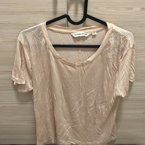 Beige kortärmad topp - Säljer en beige kortärmad topp i storlek M. Toppen är i ett mjukt och skönt material, perfekt för sommardagar eller att sova i. Den har en enkel design med rund halsringning. Aldrig använd