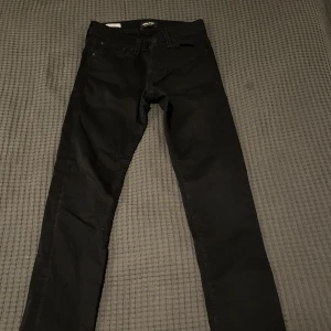 Svarta slim jeans från Jack & Jones - Säljer ett par svarta slim fit jeans från Jack & Jones, modell Glenn. De är i mycket bra skick och perfekta för både vardag och fest. Klassisk design med fem fickor och knappgylf. Passar till alla säsonger och är ett måste i garderoben!