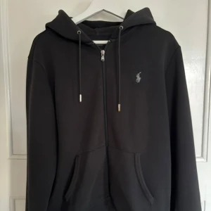 Ziphoodie från Ralph Lauren - Säljer en stilren svart ziphoodie från Ralph Lauren i mycket bra skick. Inte använd särskilt mycket. Personen på bilden är 180cm och den passar bra.