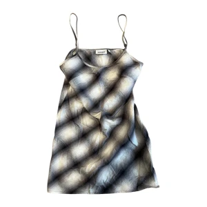 Rutig klänning - Snygg rutig klänning från Weekday med tunna axelband. Perfekt för sommardagar eller en avslappnad fest. Den har en luftig passform och är gjord i ett mjukt material som känns skönt mot huden.