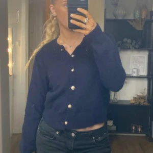 Mörkblå kofta med knappar - Säljer en snygg mörkblå kofta i mycket bra skick. Den har långa ärmar och fina knappar framtill. Perfekt för höst och vinter, och passar både till vardags och lite finare tillfällen. Koftan är i en normal passform och känns riktigt mysig att ha på sig.