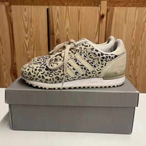 Adidas sneakers med leopardmönster - Säljer ett par coola Adidas sneakers i beige med leopardmönster. De har snörning och är i bra skick, perfekt för att ge din outfit en unik touch. Skorna är bekväma. Det står ”male” i skorna men både tjejer och killar kan ha dom. 