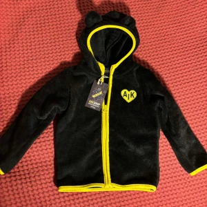 AIK-hoodie med teddyöron (baby - ny med lapp) - Supermjuk baby hoodie med gulliga öron på luvan. Officiell AIK-merch. Oanvänd med lapp kvar.  Storlek: 86/92