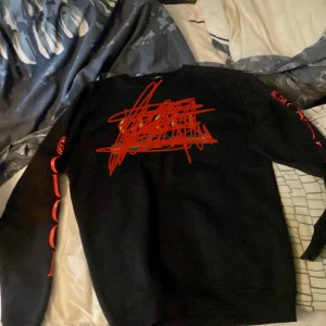 Svart långärmad tröja från G u c c i  - Säljer en svart långärmad tröja med cool röd text på både framsidan och ärmarna. Perfekt för höst och vinter, och den har en skön passform. Passar bra till både vardag och chillkvällar. Hör av dig vid intresse!