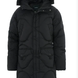 Svart dunjacka från Peak Performance - Säljer en svart dunjacka från Peak Performance i mycket bra skick. Jackan är perfekt för vintern med sin quiltade design och långa ärmar. Den har en praktisk dragkedja och knappar framtill samt en mysig huva. Perfekt för kalla dagar! ❄️ dyr i inköp, nypris 8000kr. Använd vid två tillfällen!