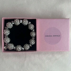 Glittrigt armband - Snyggt och glittrigt armband med större silverfärgade pärlor. Armbandet har en elastisk passform och ett litet hjärthänge. 💕🩷