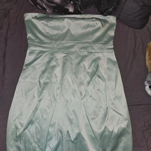 Mintgrön axelbandslös klänning från JC - Säljer en superfin mintgrön axelbandslös klänning från JC i storlek M. Den har en dragkedja bak och är perfekt för sommarens fester. Klänningen är i ett glansigt material som ger en lyxig känsla. Passar både till vardag och fest!