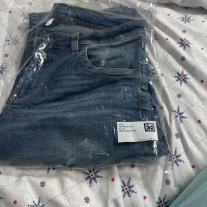 Blå jeans i förpackning - Säljer ett par klassiska blå jeans som fortfarande ligger i förpackningen. Perfekta för vardagsbruk med en snygg tvättad look. De har en traditionell femficksdesign och ser ut att vara i nytt skick. Perfekta för både höst och vår!