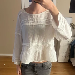 Vit blus från H&M Conscious Collection - Säljer en superfin vit blus från H&M Conscious Collection. Den har en lös passform med trekvartsärmar och är gjord i ett lätt och luftigt material. Blusen har fina detaljer med veck framtill. Mycket fint skick!!