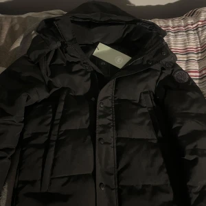 Canada goose Wyndham ”Black badge” - Säljer en svart Canada goose Jacka i mycket bra skick. Säljer den så billigt eftersom den it passar mig lika bra längre, vill bara få bort den så att jag kan köpa en annan i en storlek större eller så. Såklart är allt autentiskt. Kan mötas upp i Stockholm och byta mot en canada goose jacka samma modell i storlek XL.