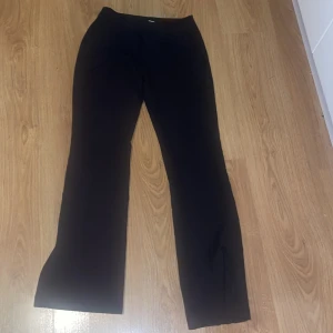 Svarta kostym byxor från BikBok - Snygga svarta byxor från BikBok i storlek 34. De har en klassisk och stilren design med en rak passform. Perfekta för både vardag och festliga tillfällen. Byxorna är i mycket bra skick, har själv aldrig användt dem då de är en storlek för små för mig och köpte här på plick så kan ej skicka tillbaka. Köparen står för frakten!! 