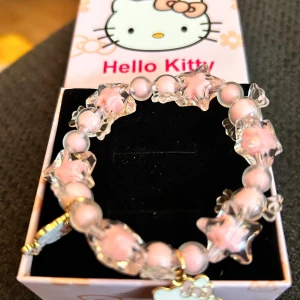 Fint elastiskt armband med Hello Kitty-motiv!  - Superfint elastiskt armband med rosa pärlor och Hello Kitty-berlocker. Kommer i matchande presentask. Allt nytt! 