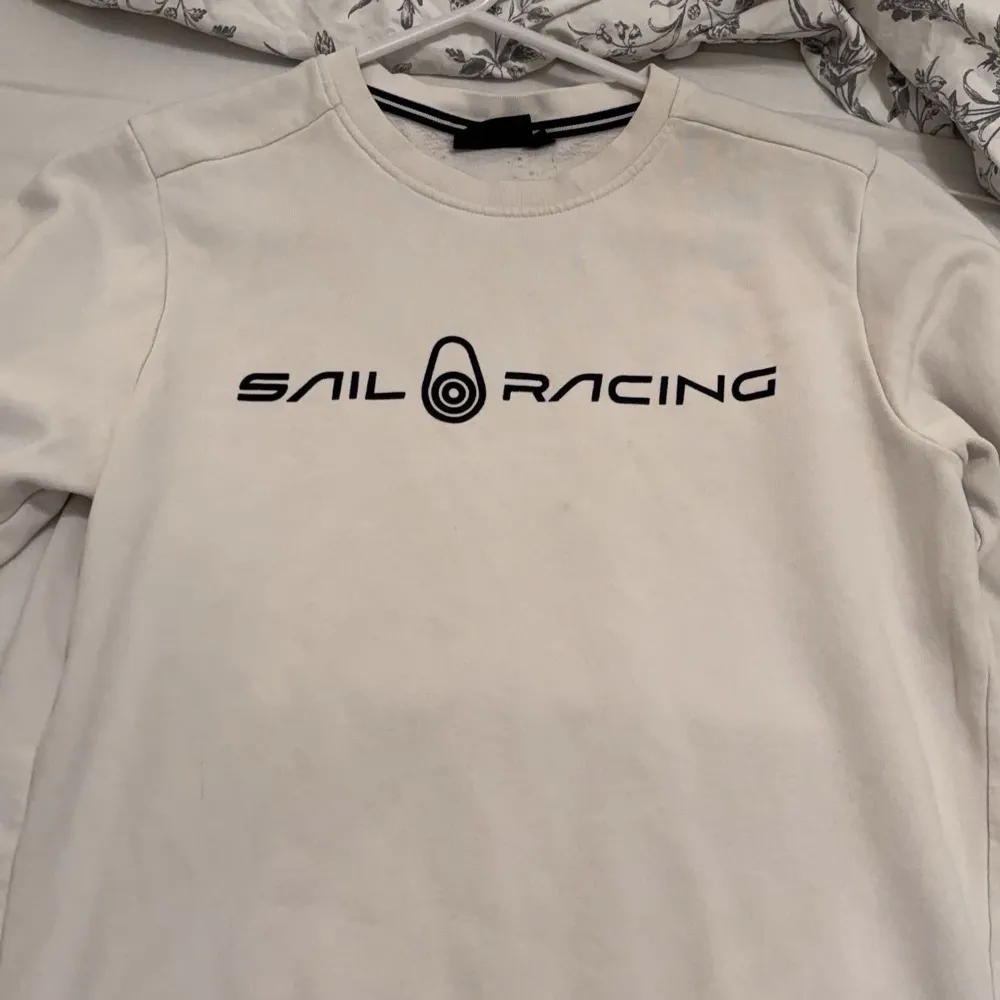 Säljer en stilren vit tröja från Sail Racing i mycket bra skick. Den har en enkel design med svart text på bröstet. Perfekt för en avslappnad stil eller som ett lager under jackan. Passar både till vardags och lite sportigare tillfällen. Passar XS/S. Tröjor & Koftor.