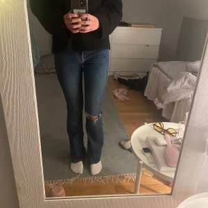Mörkblå jeans med slitningar - Säljer ett par snygga mörkblå jeans med ett hål i ena knät.De har en klassisk femficksdesign och är i bootcut-stil. Säljer då jag inte använder dom.De är i bra skick och har en bekväm passform. Inga defekter💗Kom gärna med pris förslag!!