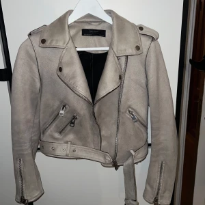 Beige skinnjacka från Zara Basic - Säljer en snygg beige skinnjacka från Zara Basic i storlek XS. Jackan har en cool bikerstil med dragkedjor och bälte i midjan. Perfekt för höst och vår! 🧥✨