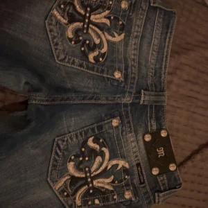 miss me jeans - Snygga blå jeans med unika broderade detaljer på bakfickorna. De har en klassisk femficksdesign och är i bra skick. Perfekta för en casual look med en twist. Passar till både vardag och fest!