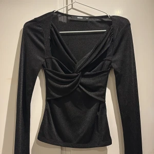 Svart långärmad topp från Bik Bok - Snygg svart långärmad topp från Bik Bok i storlek XS. Toppen har en unik draperad design framtill som ger en cool twist. Perfekt för både vardag och fest! 🖤