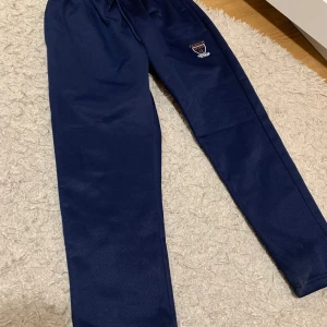 Mörkblå mjukisbyxor från AX - Säljer ett par mörkblå mjukisbyxor från AX i storlek 38. De har en elastisk midja med snörning och en liten broderad logga på sidan. Perfekta för en avslappnad dag hemma eller en promenad i parken. Superbekväma och stilrena! 💙