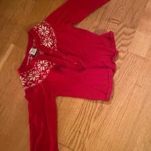 Röd kofta från Polarn O. Pyret - Säljer en superfin röd kofta från Polarn O. Pyret i storlek 104. Den har ett snyggt vitt mönster runt halsen och knappar framtill. Perfekt för kyliga dagar och passar både till vardags och fest. 🧣✨
