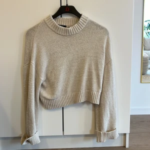 Beige stickad tröja från Gina Tricot - Säljer en superfin beige stickad tröja från Gina Tricot i storlek S. Den är croppad med långa ärmar och har en ribbad kant vid halsen, ärmsluten och nederkanten. Perfekt för höst och vinter för en mysig look! 🧶