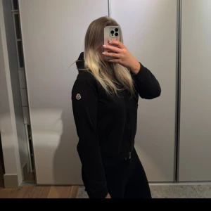 Moncler kofta - Säljer min svarta kofta från Moncler. Den är i storlek S och har en huva samt dragkedja framtill. Den har inga defekter alls och har används ett fåtal gånger 🌸Pris kan diskuteras vid snabb affär