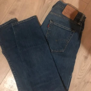 Blå jeans från Levi's - Snygga blå Levi's 512 jeans med klassisk design. De har en rak passform och är perfekta för en avslappnad stil. Jeansens blå färg ger en tidlös look. Skriv vid frågor! Pris kan diskuteras