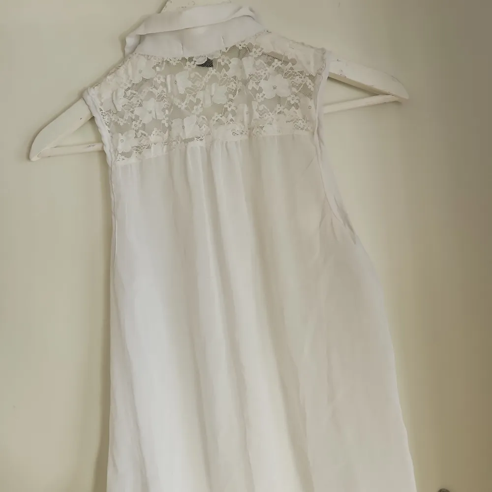 Vit tunn blus med spetsdetaljer. . Puserot.