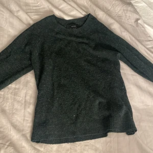 Mörkgrön tröja från Vero Moda - Säljer en mörkgrön tröja från Vero Moda. Tröjan har en enkel design med långa ärmar och ribbade kanter. Perfekt för kyligare dagar.