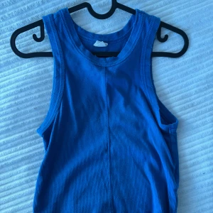 Blå ribbad linnetopp - Säljer en blå ribbad linnetopp i storlek S. Perfekt för varma dagar med sin ärmlösa design och bekväma passform. Ett måste i garderoben för en avslappnad stil.