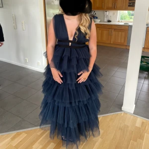 Ärmlös långklänning med volanger - Elegant ärmlös långklänning med djup v-ringning och flera lager av volanger. Marinblå färg. Klänningen har svarta banddetaljer i midjan som ger en snygg kontrast. Originell pris 2000kr bara använd en gång 💕💕