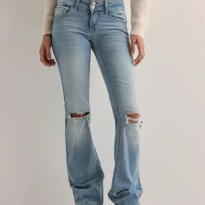 Ljusblå jeans med slitningar - Snygga ljusblå jeans med slitningar på knäna och bootcut, jeansen är från Nelly och är använda någon enstaka gång. Supersnygg men passar inte mig så bra❤️ bara fråga vid funderingar☺️