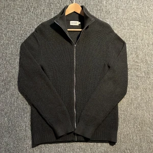 Stickad tröja  - Snygg mörkgrå stickad tröja från East West med dragkedja framtill. Tröjan har en hög krage och långa ärmar, perfekt för kyligare dagar! Storlek L men passar M-S🤩skriv pm för fler frågor!💯