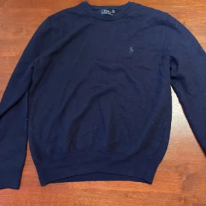 Mörkblå tröja från Ralph Lauren - Säljer en stilren mörkblå tröja från Ralph Lauren i merinoull. Tröjan har en broderad logga på bröstet och långa ärmar. Perfekt för en klassisk look. Nypris runt 2600kr. Skulle säga att den sitter bäst på S då den är lite liten i storleken. 