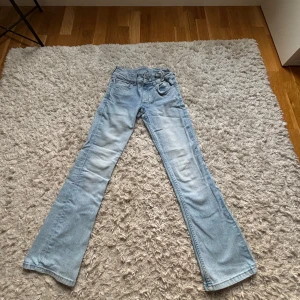 Ljusblå bootcut jeans - Säljer ett par ljusblå bootcut jeans med klassisk femficksdesign och knappgylf. De har en bekväm passform. Storlek 11-12 år, 146-152. Lågmidjade💕. Justerbar i midjan💕