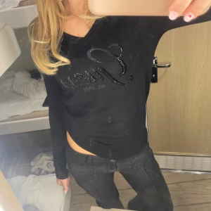 Svart långärmad tröja från Guess - Säljer en splitterny snygg svart långärmad tröja från Guess med glittrig logga framtill. Tröjan har en v-ringad hals och är perfekt för en stilren look. Passar bra till både jeans och kjol. Tröjan är inte använd, säljer den för den passade inte mig som förväntat😙