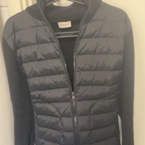 Svart Cardigan från Moncler - Snygg svart Cardigan från Moncler. Eftertraktad modell, i storlek M (som även kan passa de med S då moncler vanligtvis är något små i storleken). Passa på, då denna jacka kommer gå fort nu när våren börjar ta fart.☀️Priset är ej hugget, men endast förhandlingsbart vid snabb, seriös o smidig affär. Vill enbart ha seriösa intressenter samt köpare så därav vid fler frågor, bilder m.m så hänvisar vi er seriösa till att kontakta oss med era funderingar sp svarar vi mer än gärna där. //Västkustenoutlet