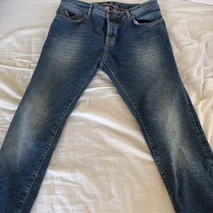 Blå jeans från New Zealand - Säljer ett par klassiska blå jeans från New Zealand. De har en snygg tvätt med lätt slitna detaljer och en knappgylf. Perfekta för en avslappnad stil.
