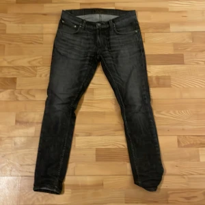 Svarta  Nudie Jeans - Snygga svarta jeans från Nudie Jeans i en slim passform. De har en klassisk femficksdesign och är tillverkade i slitstarkt denim. Perfekta för en stilren look. Kom gärna med prisförslag