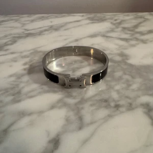 H armband  - Säljer ett snyggt H armband i mycket bra skick i färgen silver/svart.