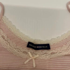 Rosa randig linnetopp från Brandy Melville - Söt rosa randig linnetopp från Brandy Melville med spetsdetaljer och en liten rosett framtill. Oanvänd💞