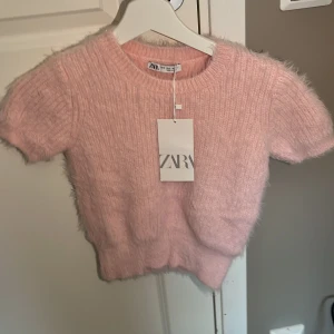 Rosa fluffig tröja från Zara - Säljer en supermjuk och fluffig rosa tröja från Zara. Den har korta ärmar och en rund halsringning, perfekt för en mysig look. Tröjan är i storlek S och har en härlig textur som ger en unik stil. Passar perfekt för både avslappnade och mer uppklädda tillfällen. 🌸