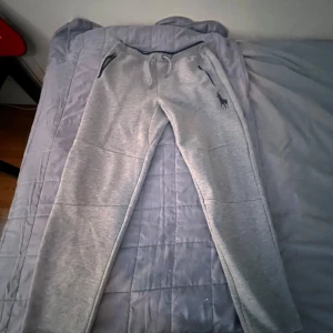  mjukisbyxor polo Ralph lauren - Snygga grå mjukisbyxor från Ralph Lauren med en liten broderad logga på sidan. Byxorna har snörning i midjan och är perfekta för en avslappnad stil. De har en normal passform och är gjorda i mjukt material för extra komfort.