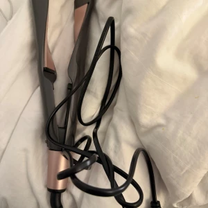Plattång från remington - Säljer en stilren plattång från remington i svart och roséguld. Den har en sladd och en smidig design för enkel användning. Perfekt för att styla håret snabbt och effektivt. Formen är perfekt för lockar och gör det enklare att få till fina lockar.