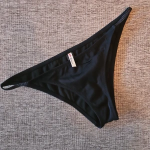 Svart bikiniunderdel - Snygg och stilren svart bikiniunderdel. Perfekt för en dag på stranden eller vid poolen. Den har en enkel design med smala sidor för en modern look.