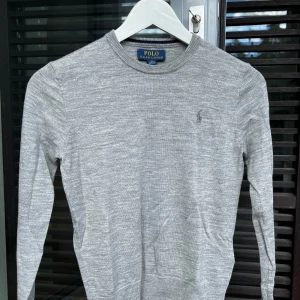 Ralph Lauren Extra fin merino ull strl 140 - Superfin ljust grå Ralph Lauren tröja i fin merino ull. Tröjan är tunn och Inget stickigt material utan känns nästan som Kashmir. Ljusgrå häst broderad på vänster sida. Köpt på NK för 1300 kr.  Storlek 10 år 