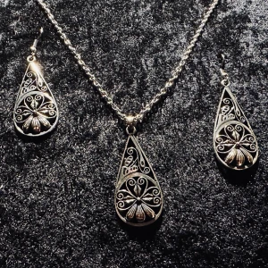 Elegant silverfärgat matchande smyckeset med halsband och örhängen Bohemisk Hippie Bohochic Alternativ Goth Gotisk - Säljer ett superfint smyckeset i silverfärg som består av ett halsband och matchande örhängen. Både halsbandet och örhängena har en droppformad design med intrikata mönster och detaljer som ger en bohemisk vintagekänsla. Örhängena är 5,8 x 2,2 cm. 