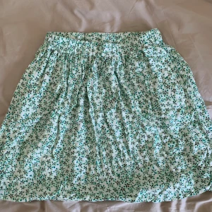 Blommig kjol  - Blommig kjol från Nelly. Sparsamt använd så väldigt bra skick. Färgerna syns bäst på sista bilden. Kjol har fickor och går till litenovanför knäna.
